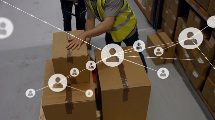 Personale del magazzino che impila scatole per la spedizione mentre un lavoratore inginocchiato solleva una scatola, con una sovrapposizione che copre il pallet.