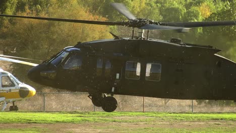 Pan-shot-following-a-black-Helicopter-landing-on-a-field-in-sunny-Los-Angeles,-USA