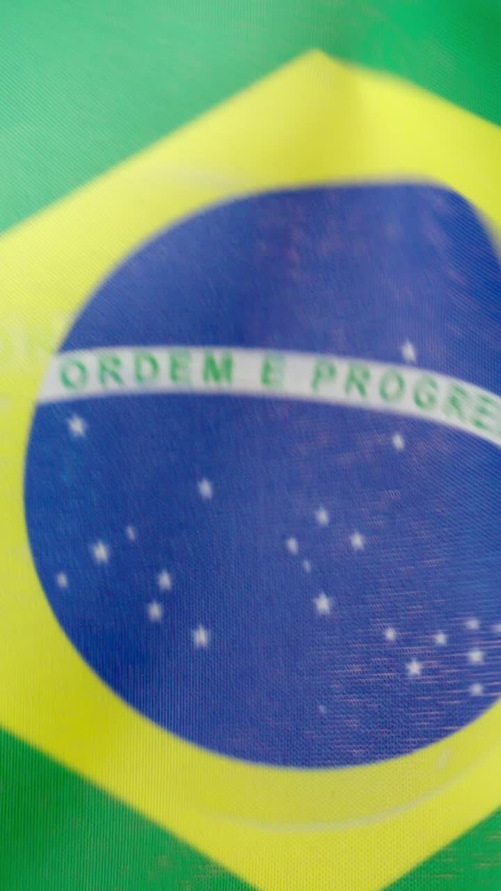 Vertical video of brazilian national flag waving by the wind