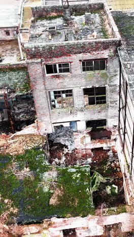 debris and construction garbage inside and outside the broken factory buildings. ruined plant exterior from aerial perspective. vertical video