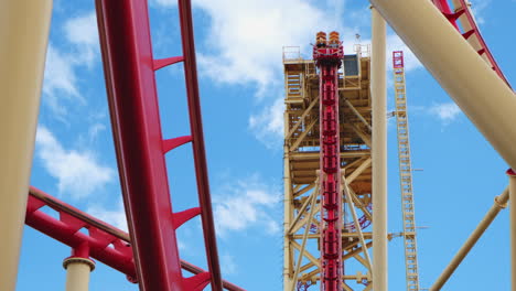 Tracking-shot-of-Rollercoaster-riding-on-rail-tracks-against-blue-sky-during-sunny-day