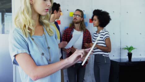 woman using digital tablet with her colleagues in background 4k