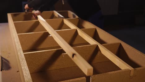 carpenter assembling wooden shelving unit