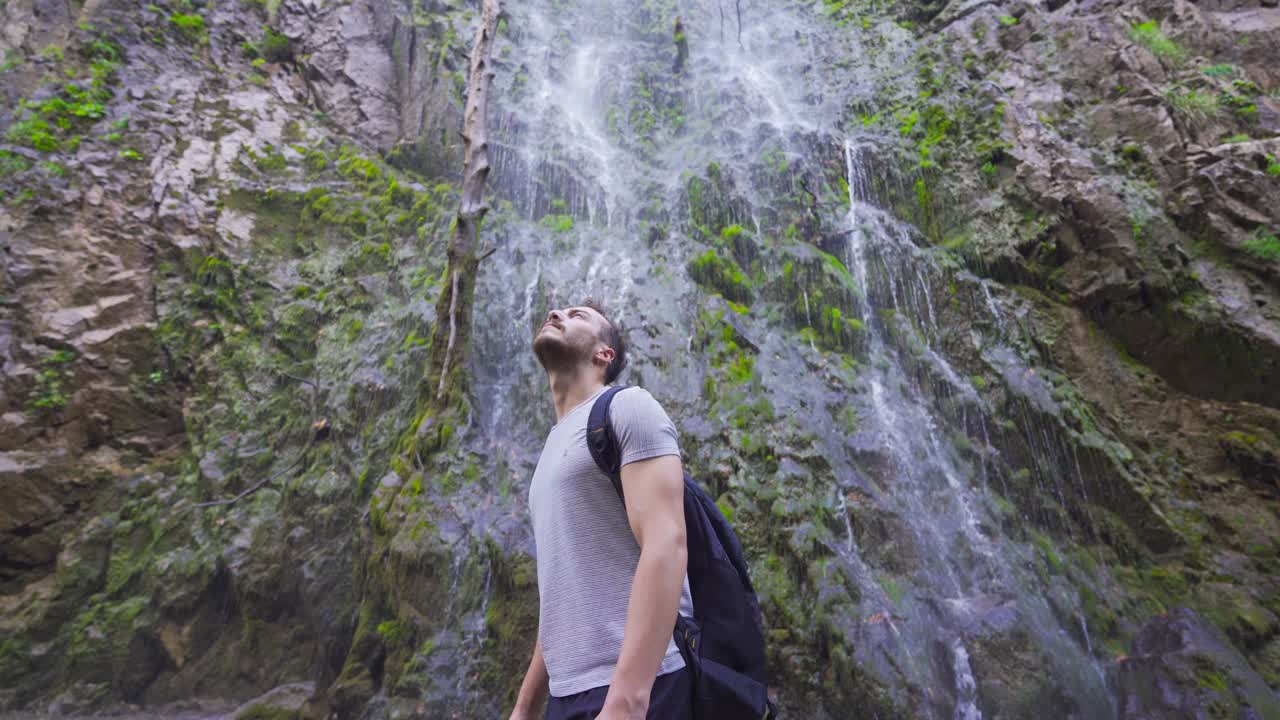 el joven se da la vuelta frente a la cascada.