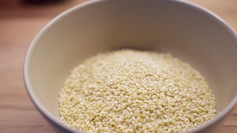sesame seeds in a bowl on a wooden surface