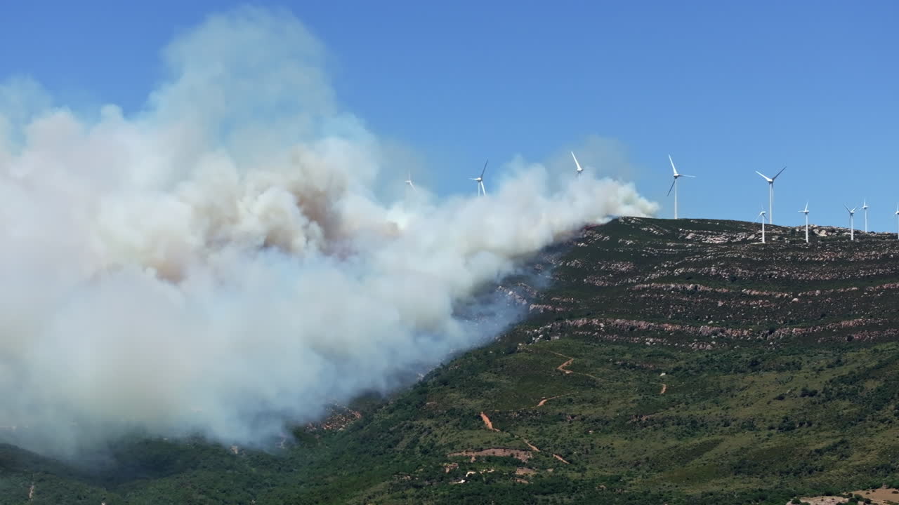 Wildfire engulfs the mountain peak of Valdevaqueros in Tarifa, Spain. Flames rage to the summit due to extreme heat and dryness, creating a dramatic and destructive scene.