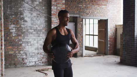 african american man exercising with medicine ball in an empty urban building