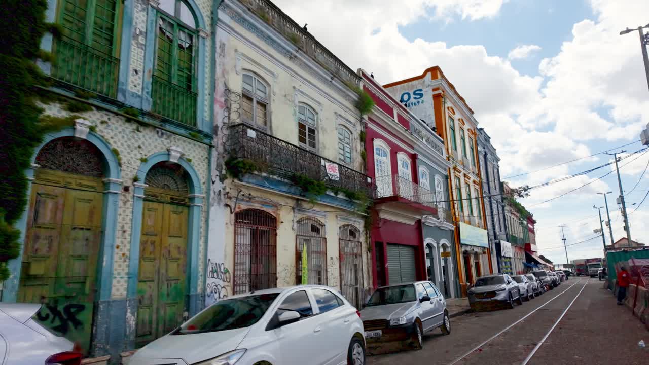 Vibrant and Worn Historic Buildings Line a City Street with Railway Tracks