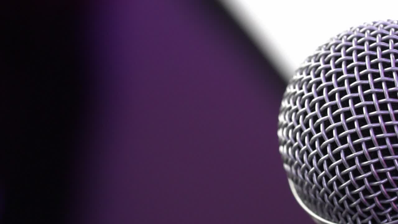 Close-up of microphone against purple background, highlighting performance mood