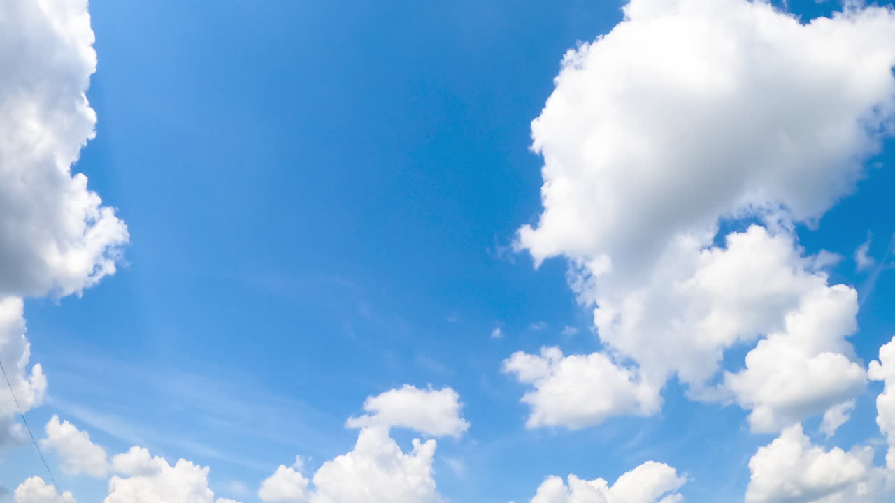 Bright summer sky with white soft clouds. Sun lighting the beautiful cloudscape. Low angle view. Timelapse.