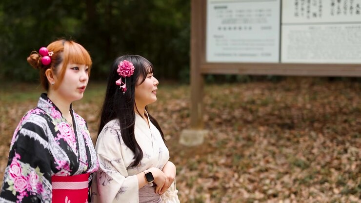 Due donne asiatiche che indossano yukata tradizionali stanno all'aperto in un parco di Tokyo in autunno