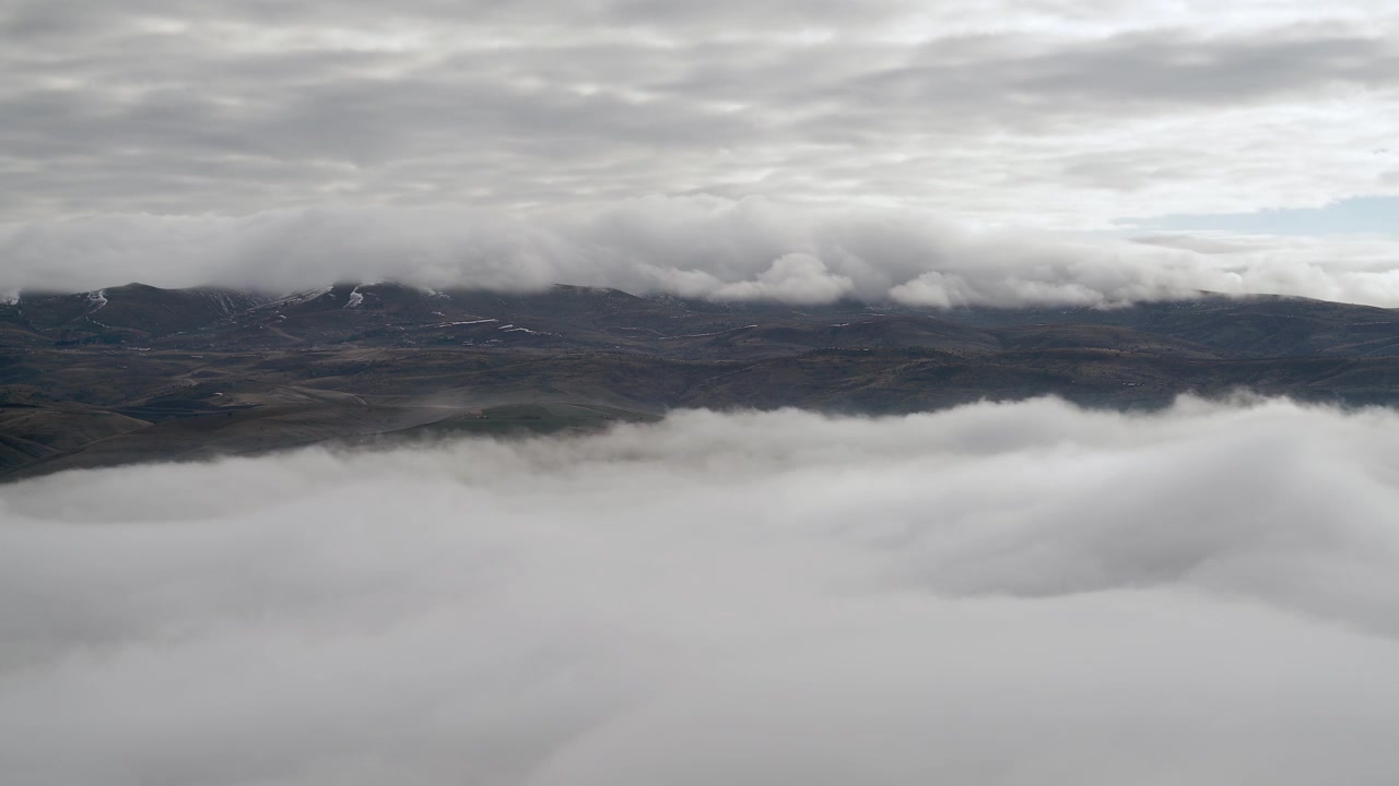 Aerial View of Thick Clouds Rolling Over Mountain Range