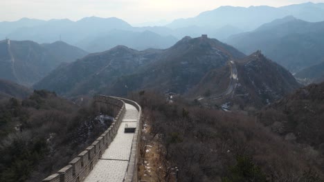 experience a breathtaking reveal of the great wall of china as it extends through the mountains, captured in slow motion. the serene beauty of distant peaks complements this stunning vista.