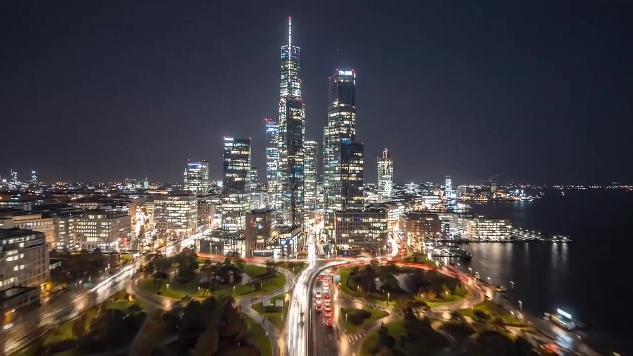 Uno Scrocio di Vita Urbana: Affascinante Vista Notturna della Città da Sotto il Ponte verso gli Imponenti Grattacieli Illuminati dalle Luci della Città e dai Riflessi