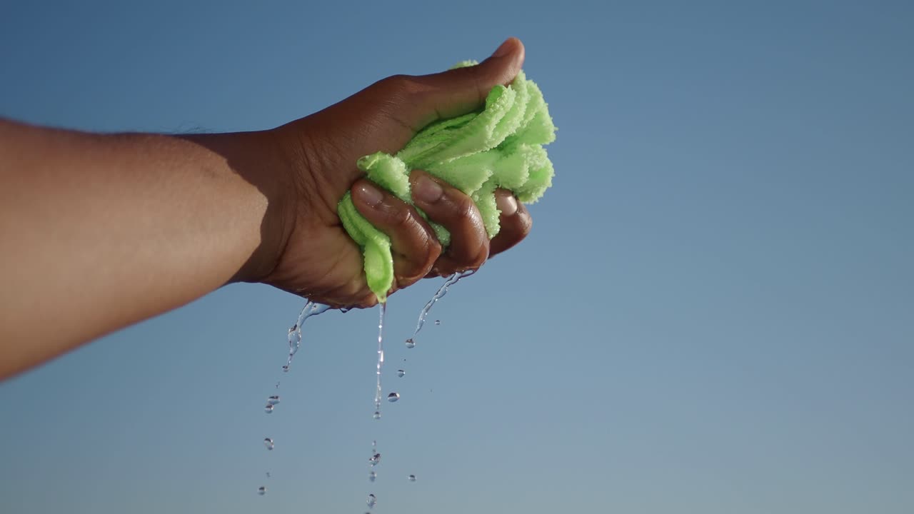 la mano apretando una toalla verde húmeda