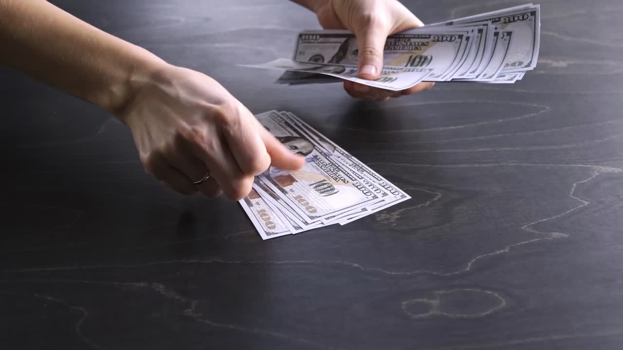 4K. The woman counts the money. 100 USA dollar banknotes bundle. Counting process. World economic crisis. Bribe. Dirty money concept. Puts on wooden table. Side view. Close-up. Hundred. Video footage