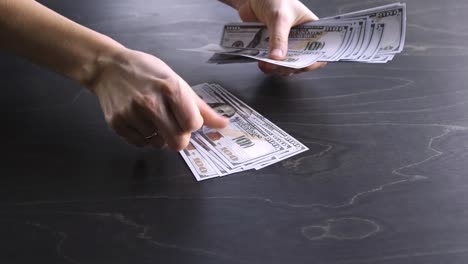 4k. la mujer cuenta el dinero. paquete de billetes de 100 dólares estadounidenses. proceso de conteo. crisis económica mundial. soborno. concepto de dinero sucio. pone en una mesa de madera. vista lateral. primer plano. cien. imágenes de video