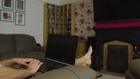 hombre reclinado usando el mouse en una computadora portátil en la sala de estar