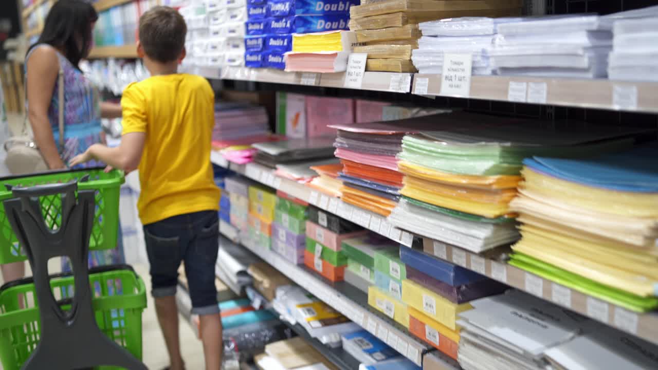 Kid in shopping mall. Young boy choosing school stationery in store