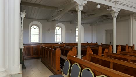 tracking view along front of lutheran church sanctuary, rows of old wooden pews