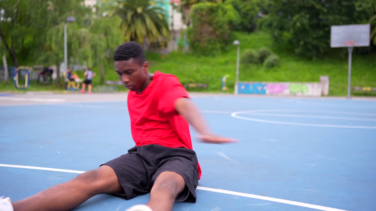 Young Man Stretching on a Basketball Court