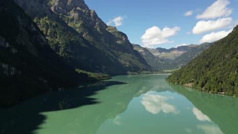 enormous valley created by surrounding mountains and hills covered by forest trees and rocks creating wonderful location for this pure crystal clear body of water to run through mirror effect reflect