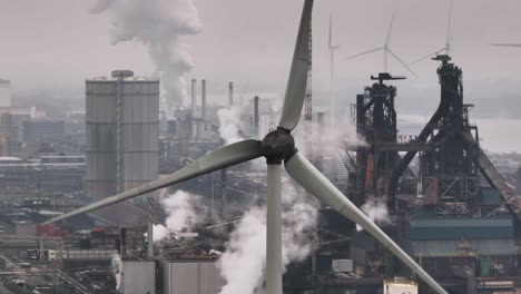Juxtaposition of wind turbines in smoggy industrial area, Europe, aerial