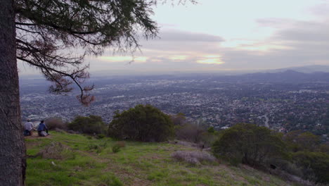 a drone shot of two hikers on top of a mountain look out over a scenic overlook