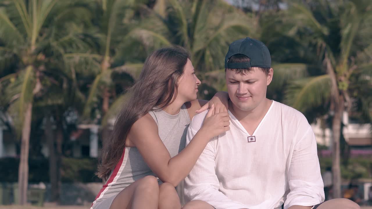 mujer joven en vestido pone las manos y la cabeza en el hombro del tipo