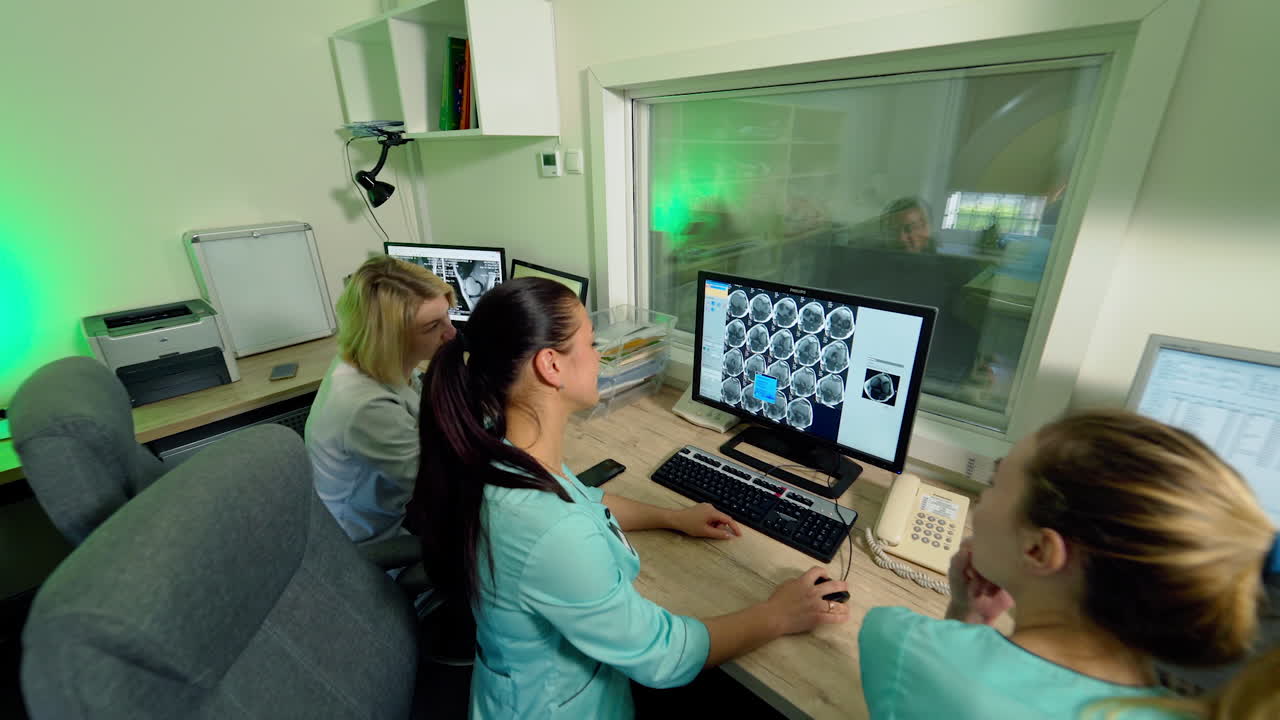 Medical control room with specialists in hospital. Doctor radiologist and medical workers discuss the diagnosis while watching at monitor patient's scan results.