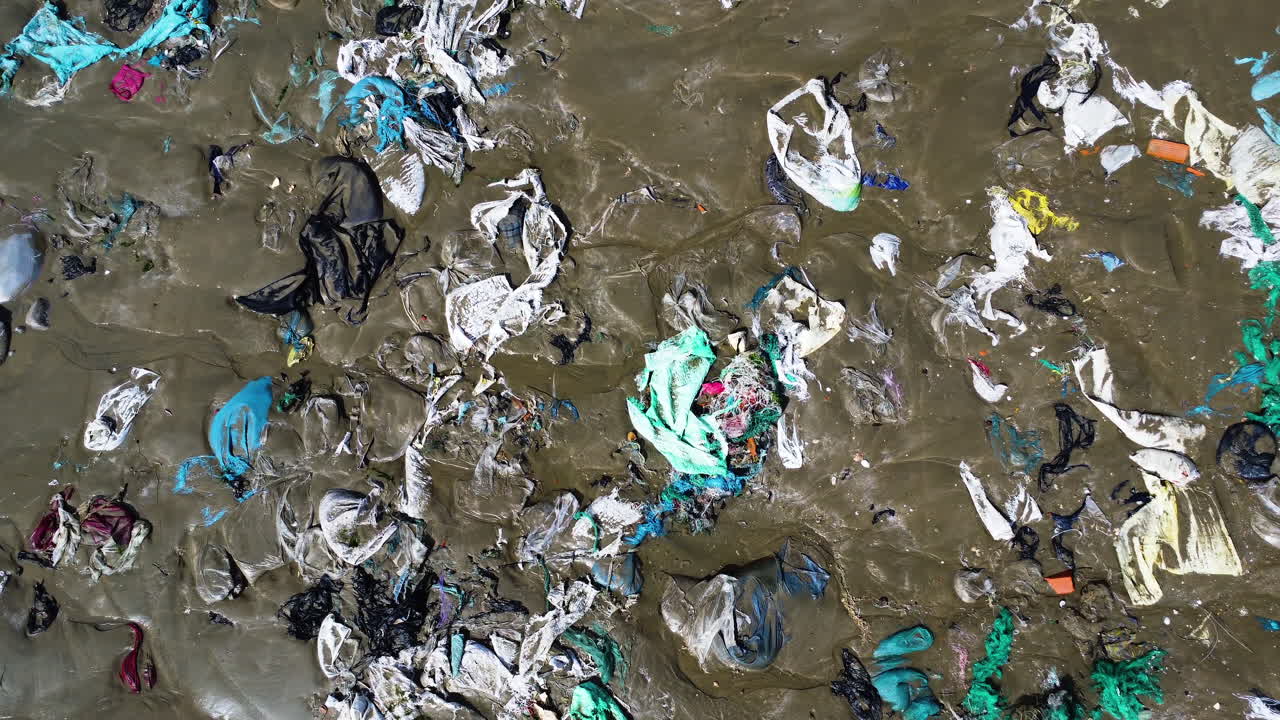 bolsas de plástico esparcidas en la arena de la playa