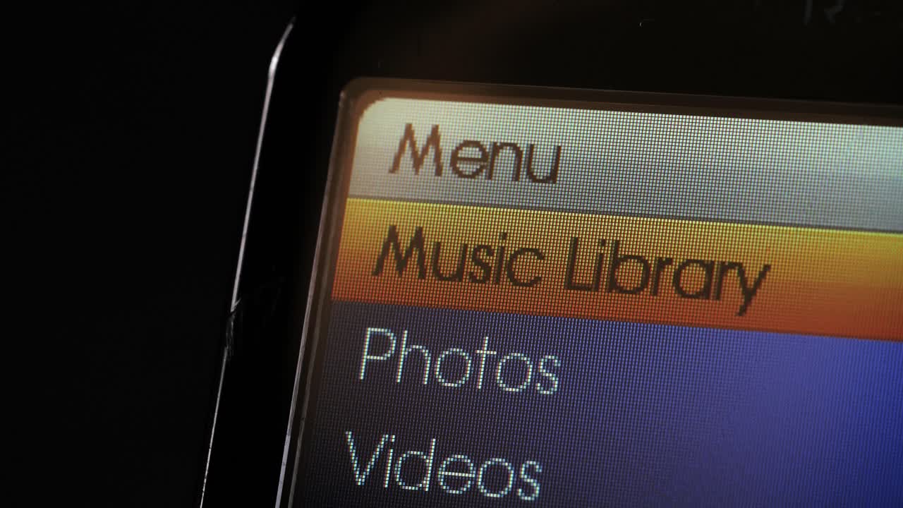 Close up of a retro portable music player menu scrolling through options for music, photos and videos
