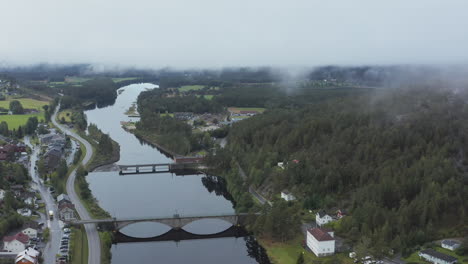 aerial drone view over the amfoss bridge on the nidelva river, in the aamli town, dark, foggy day, in south norway