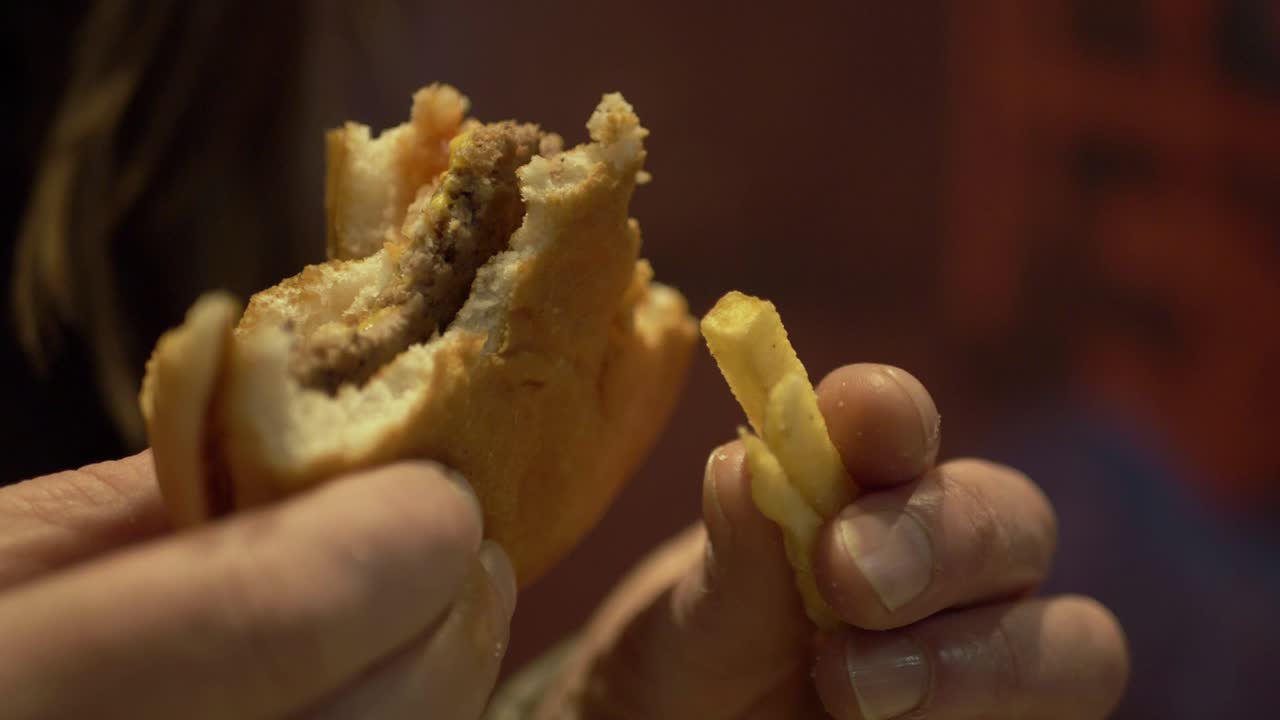 mujer sosteniendo hamburguesa con queso y papas fritas primer plano