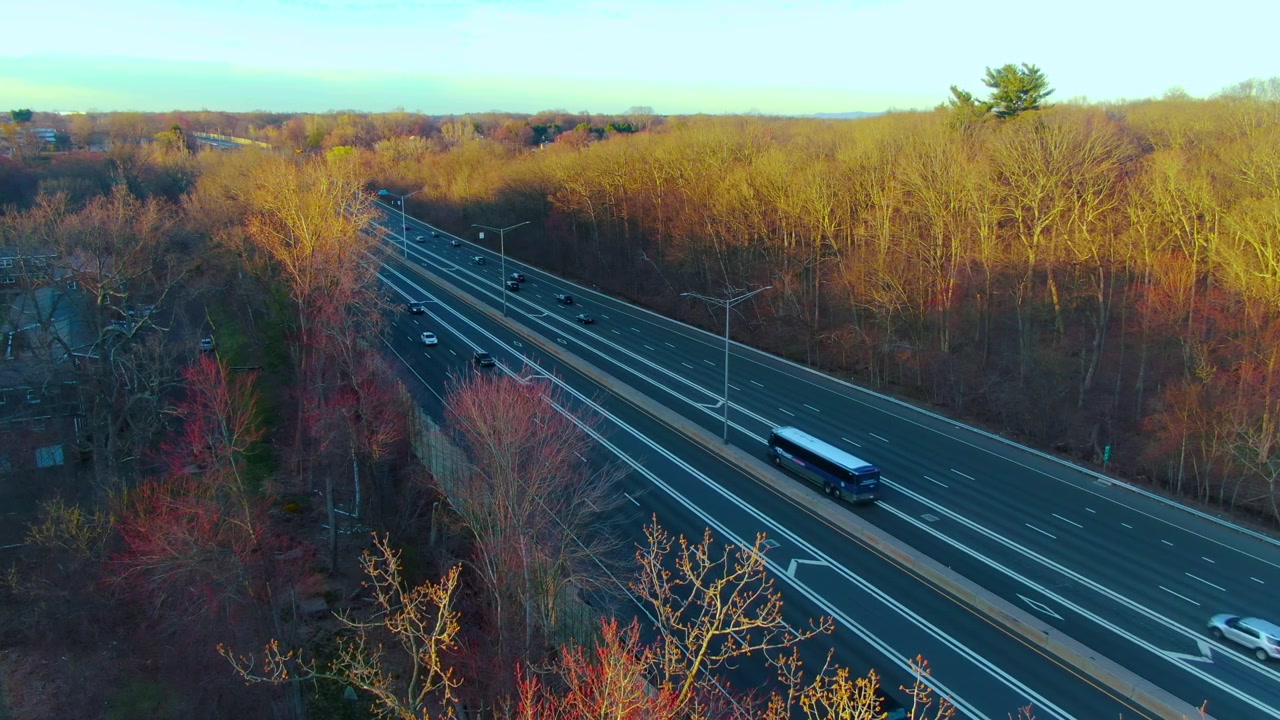 Drohnenaufnahme, die eine statische Luftansicht einer Autobahn mit fahrenden Fahrzeugen zeigt, umgeben von Bäumen an einem Frühlingsnachmittag in Windsor, Connecticut