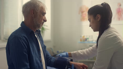 Senior-man-undergoing-medical-examination-in-clinic.-Doctor-measuring-pressure.