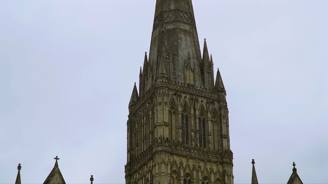 Close-up view of the towering Gothic spire of Salisbury Cathedral in Wiltshire, England, featuring intricate medieval stonework and historic architectural design