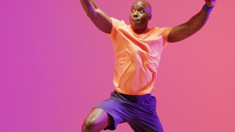 Video-of-african-american-male-basketball-player-throwing-ball-on-pink-to-orange-background