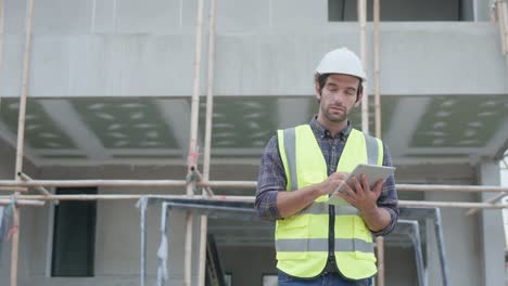 ingeniero civil profesional masculino o arquitecto usar casco de seguridad. mientras que el ingeniero guapo trabajando usando la tecnología de tableta aplicación lista de comprobación proyecto de construcción en el sitio de construcción.