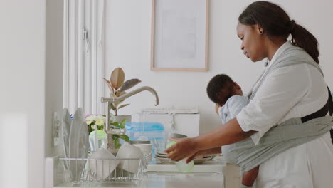 african-american-mother-holding-baby-working-at-home-washing-dishes-cleaning-kitchen-caring-for-toddler-doing-housework-enjoying-motherhood