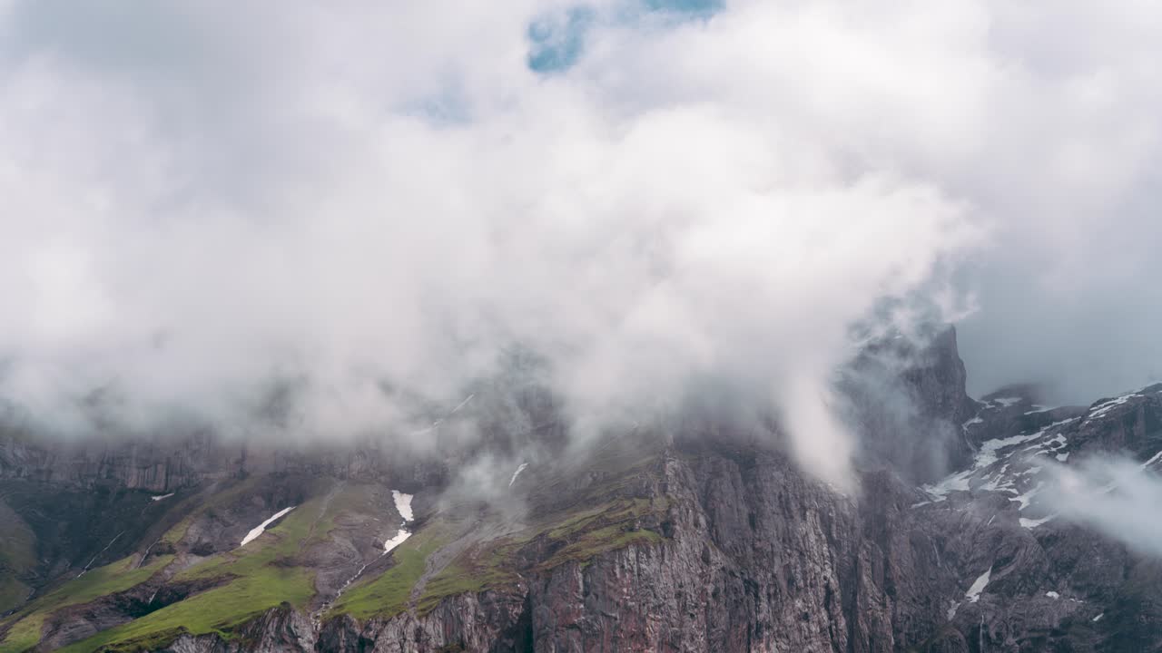 Moody alpine peaks shrouded in thick clouds near Kandersteg (Bernese Oberland region of Switzerland), with jagged cliffs and snow patches peeking through the mist for a dramatic mountain timelapse.