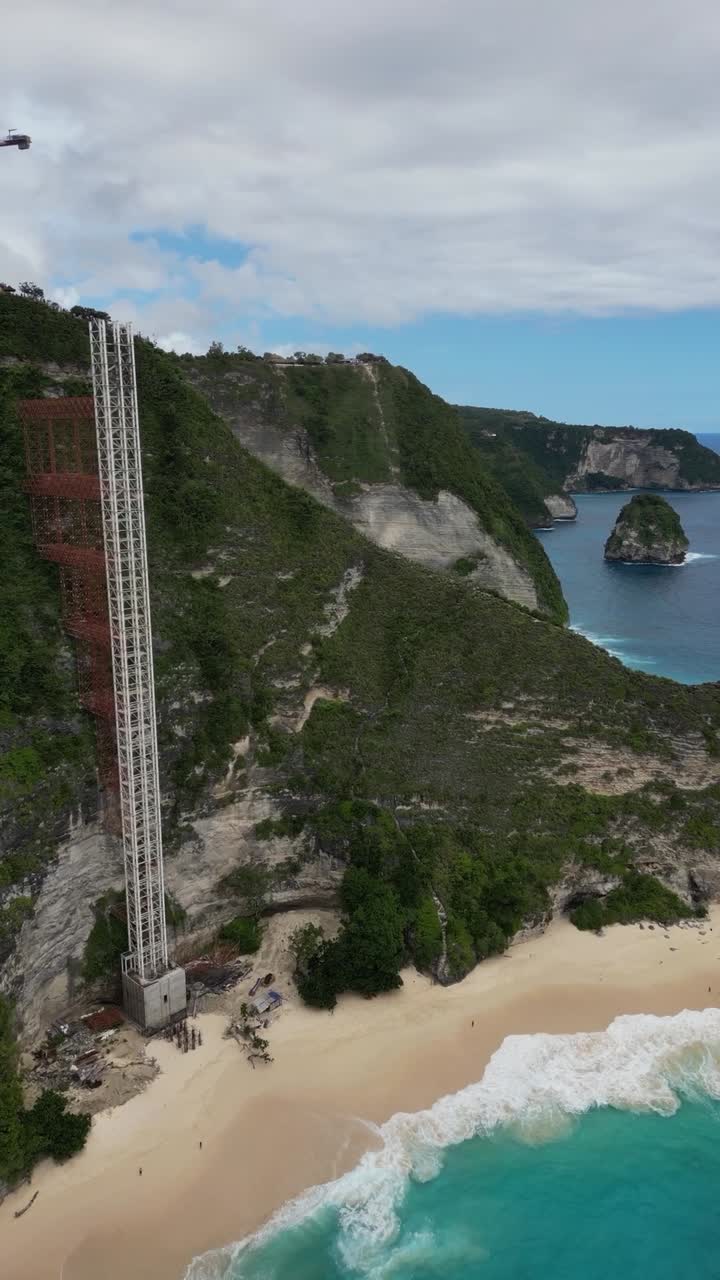 Uma tomada suave em retrato de drone da praia de Kelingking, Nusa Penida, Bali, mostrando a construção do elevador
