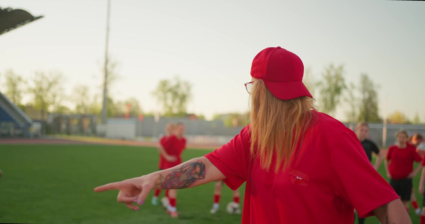Weibliche Fußballtrainerin instruiert ihr Team auf dem Spielfeld.