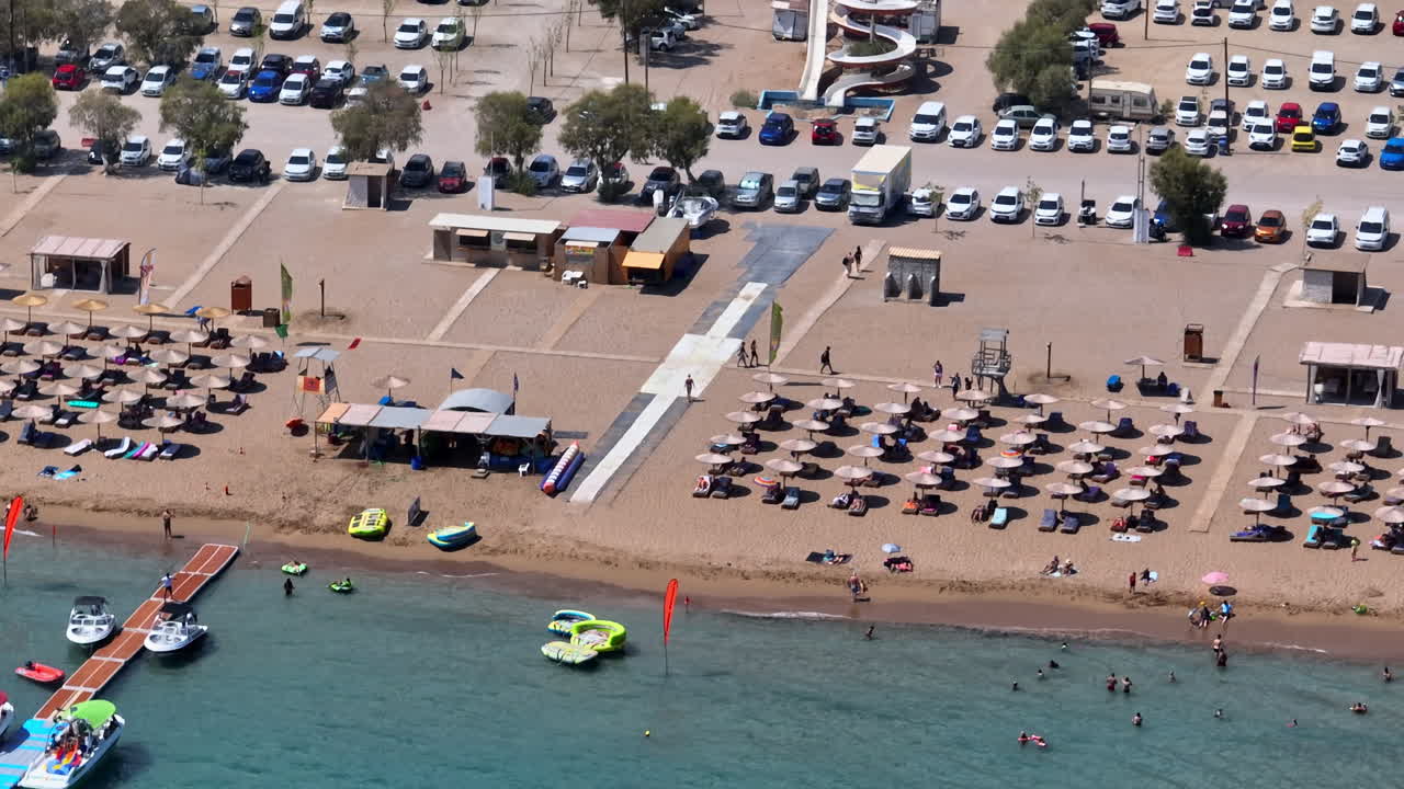 Aerial tracking shot of a busy day at the Faliraki beach, in sunny Rhodes