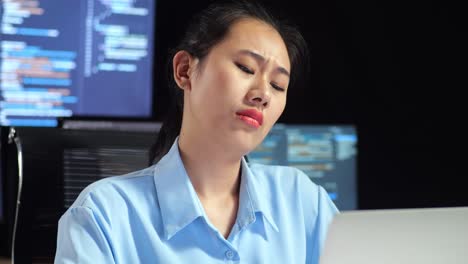 아시아 여성 프로그래머가 여러 모니터를 사용하여 노트북으로 코드를 작성하는 동안 무언가에 대해 생각하고 사무실의 터미널 창 데스크에서 데이터베이스를 표시합니다.