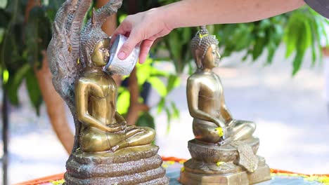 hands cleaning and polishing a buddha statue