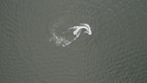 Downward angle drone shot of someone riding a jet ski