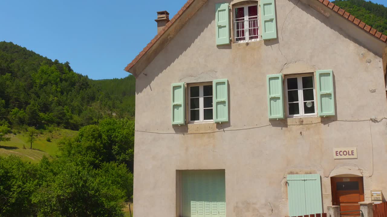 Old school building with mint shutters in Glandage, Rhône-Alpes, sunny day