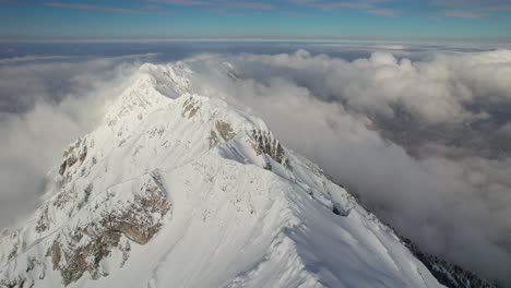 Schneebedeckter-Gipfel-Des-Piatra-Craiului-Gebirges,-Der-Sich-über-Den-Wolken-Erhebt,-Luftaufnahme,-Ruhige-Natur