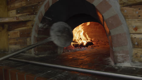 hombre afroamericano poniendo masa de pizza en el horno